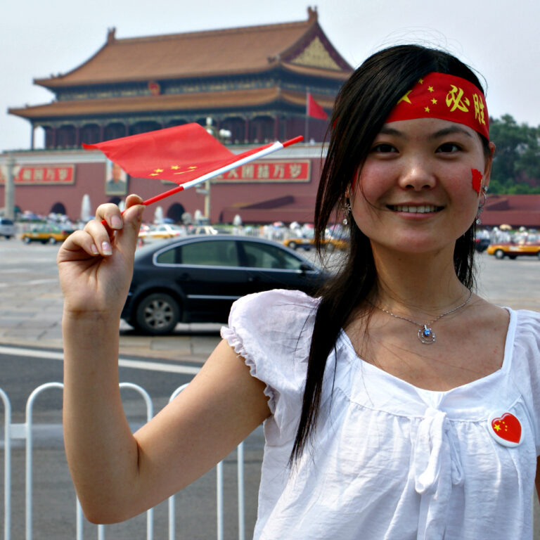 vrouw wappert met chinese vlag voor paleizencomplex verboden stad