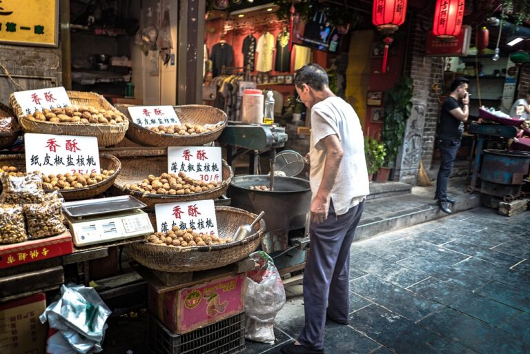 man staat voor straatvoedselkraam in china en bereidt lokale specialiteiten als noten en specerijen