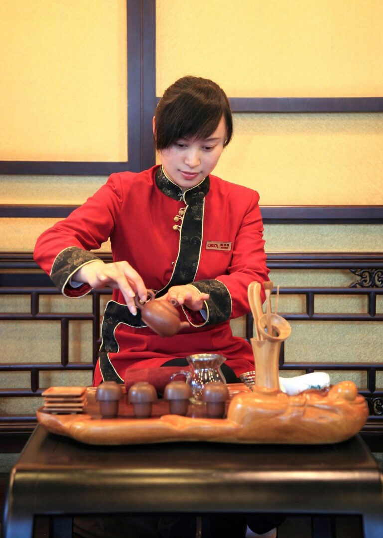 aziatische vrouw in traditioneel rood uniform voert chinese theeceremonie uit
