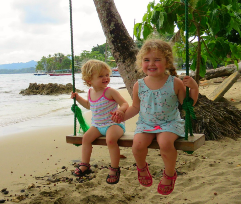 twee kleine meisjes schommelen aan het strand van costa rica