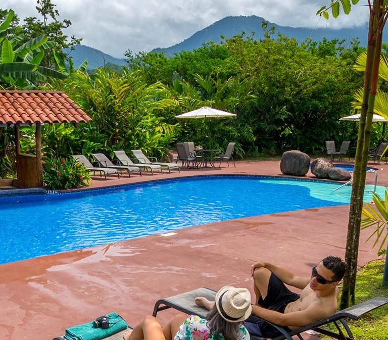 twee reizigers ontspannen aan zwembad met uitzicht op arenal vulkaan