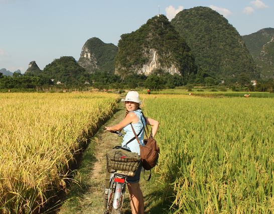 vrouw poseert met fiets bij yangshuo tussen rijstvelden en karstbergen