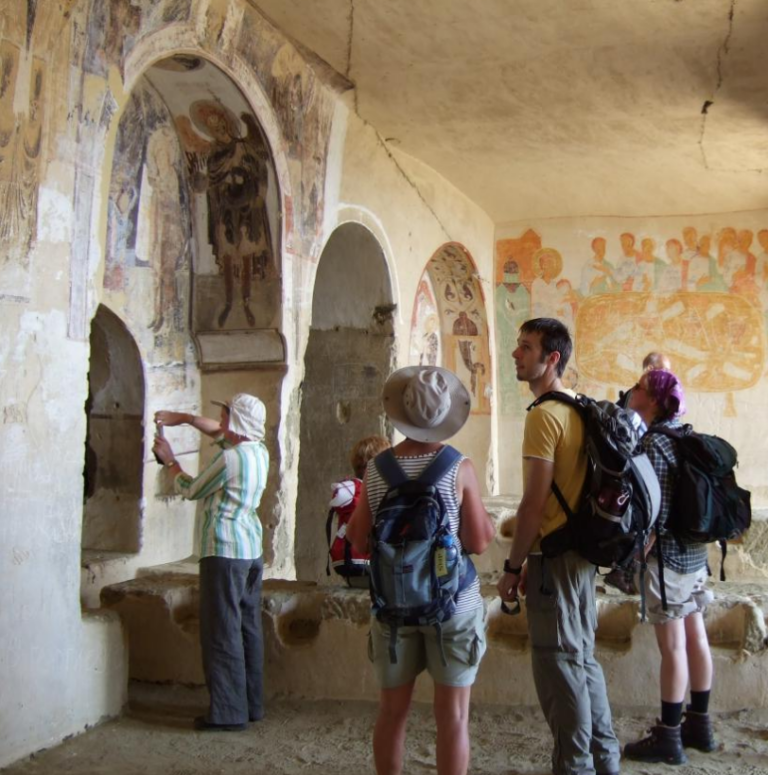 toeristen bekijken fresco's in oude kerken in david gareja