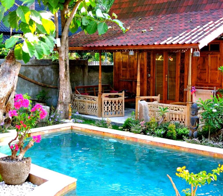 houten cabin huisje aan zwembad omringd door tropische blioemen en planten op Gili Trawangan
