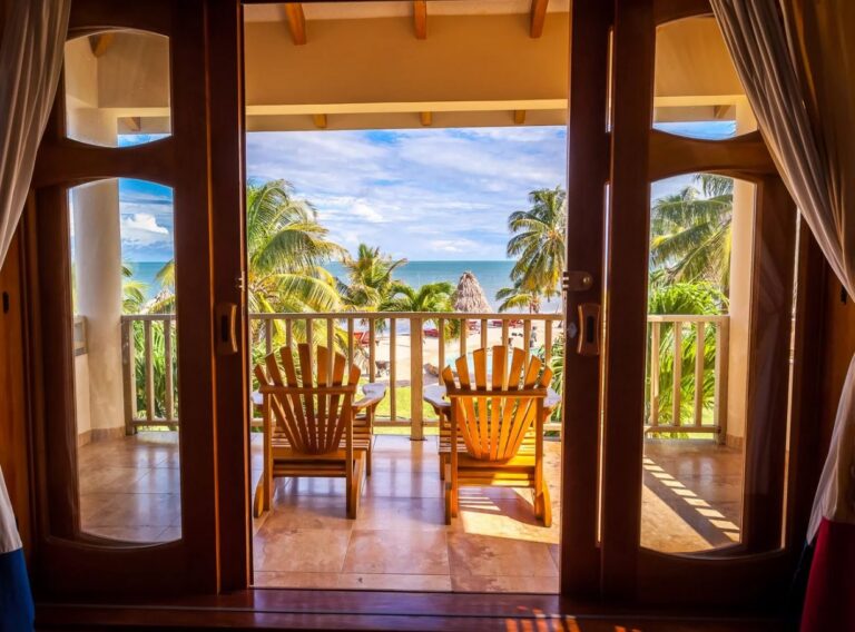 Balkon van een kamer bij Hopkins Bay Resort met zitje en uitzicht op strand en zee in Belize