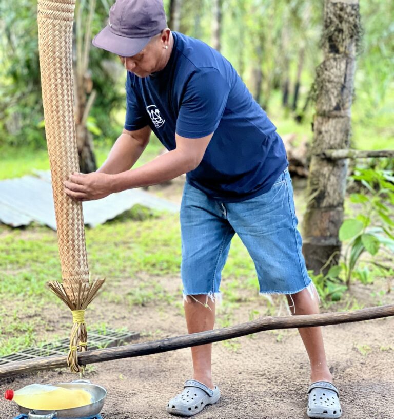 een local laat het gebruik van de matapi zien, een cassave pers, gebruikt door de inheemse bevolking van Suriname