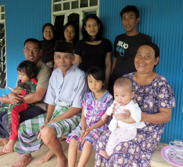 lachende groep indonesische familieleden poseert voor hun eigen huis