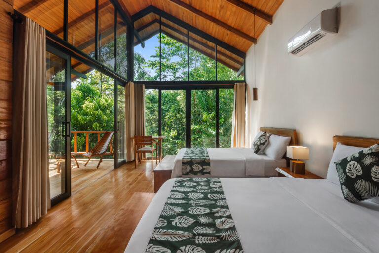 een hotelkamer met veel lichtinval door de grote ramen in de jungle