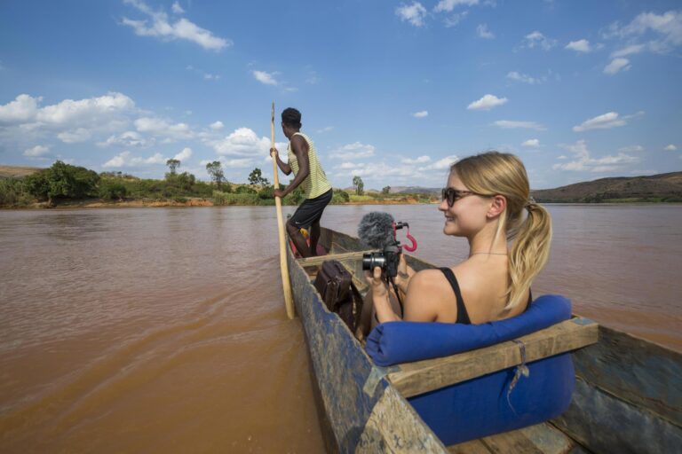 Reiziger in bootje met camera waarbij local boot bestuurt en op het water in Madagaskar