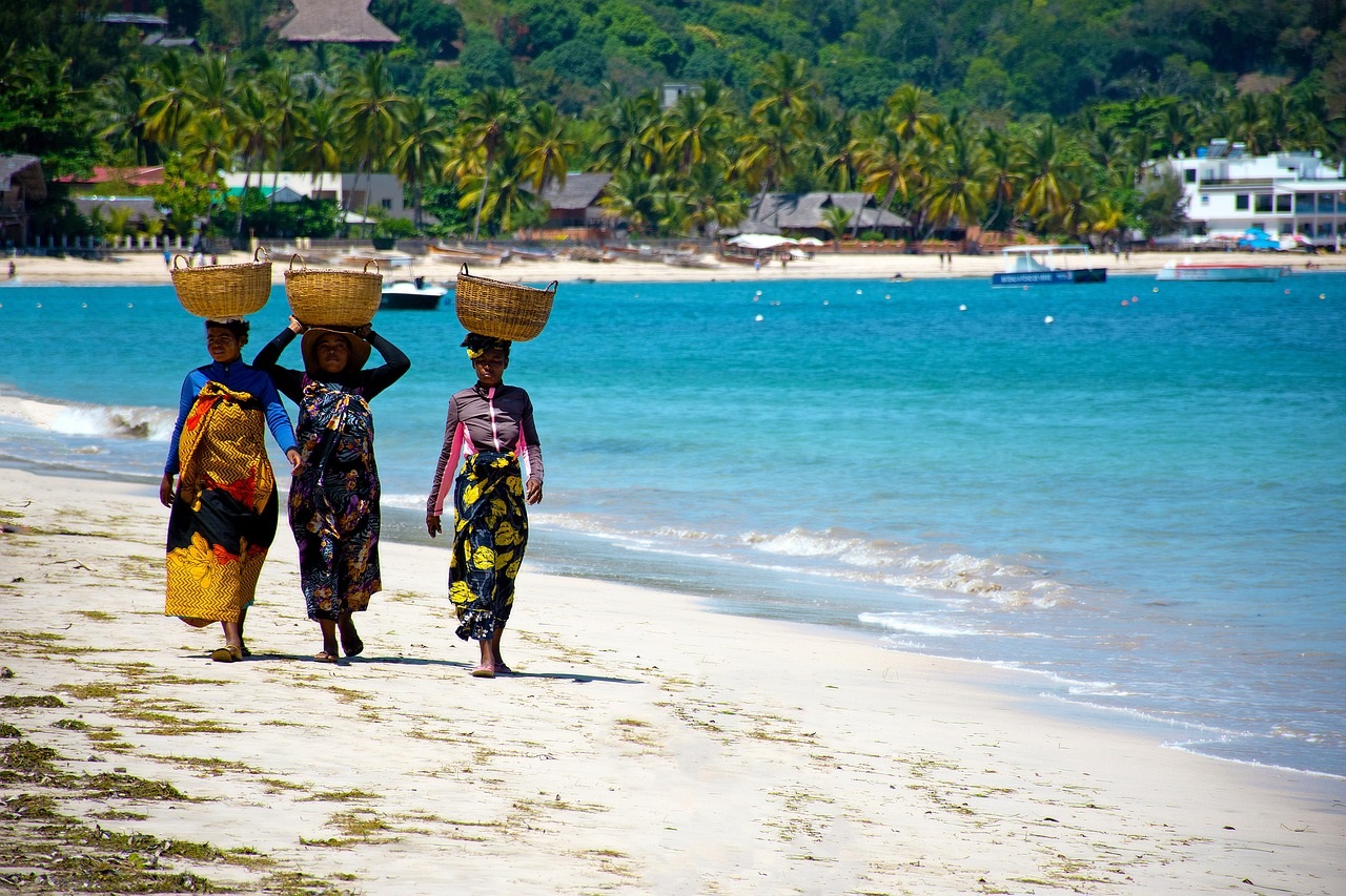 Lokale vrouwen lopend op het strand met manden op hoofd in Madagaskar