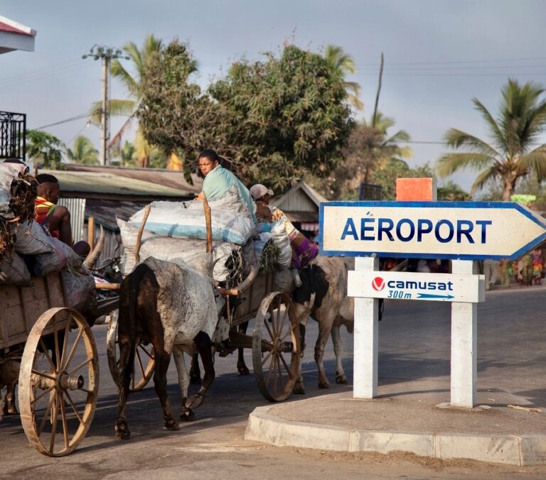Locals met koe en wagen en met een bord waar Aeroport op staat in Madagaskar