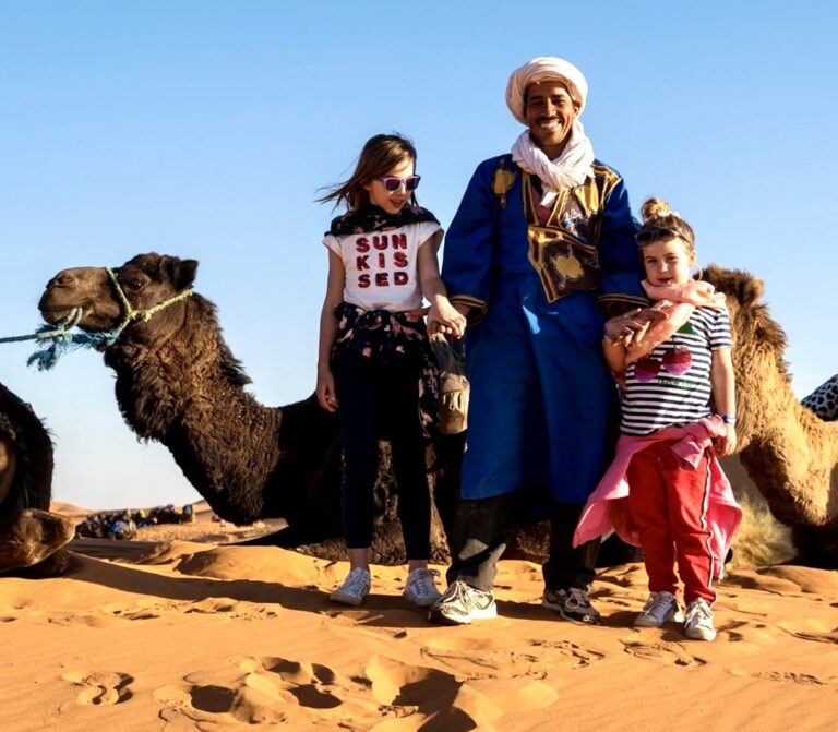 twee kinderen poseren met een Marokkaanse man voor een kameel