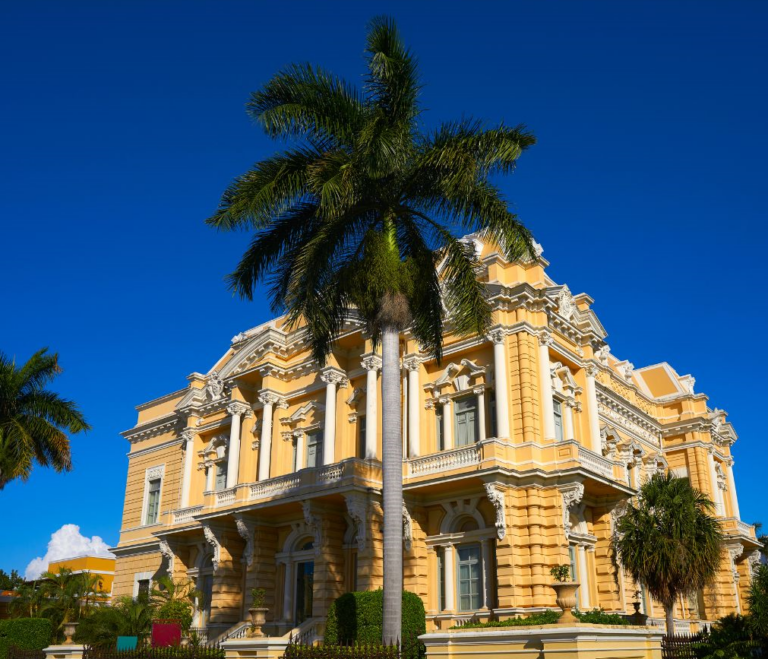 Geel gebouw met op de voorgrond een palmboom in Mérida Mexico