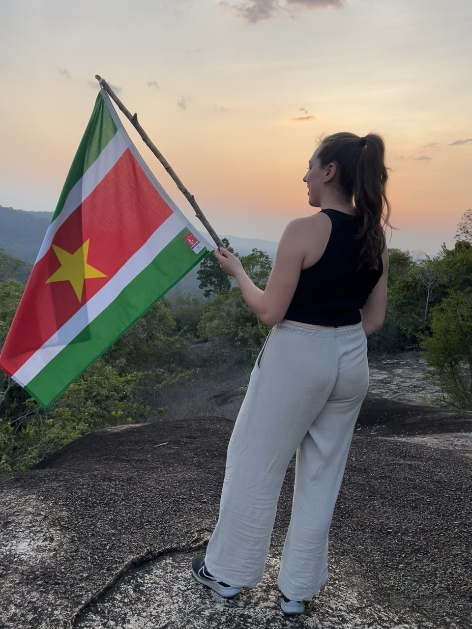 Een reizigster houdt de vlag van Suriname vast bovenop de Fredberg