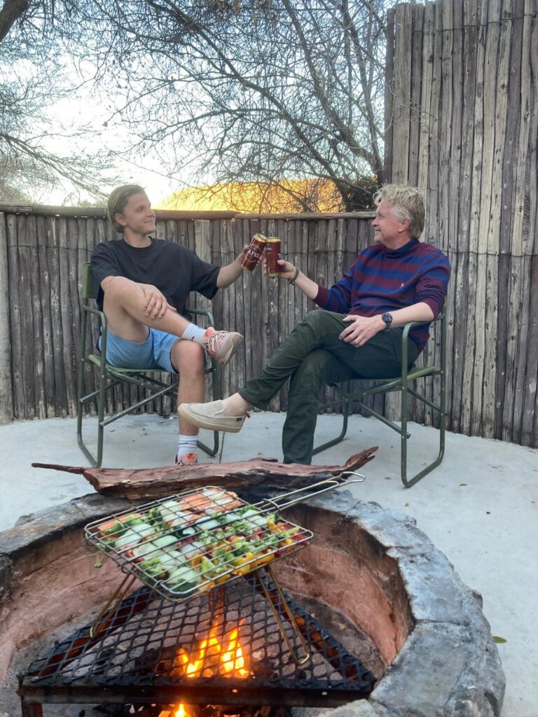 reizigers proosten met biertje bij kampvuur op hun Namibië reis