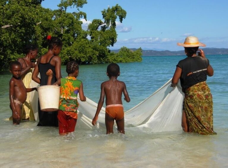 Lokale vrouwen en kinderen in het water met net om vissen te vangen in Madagaskar