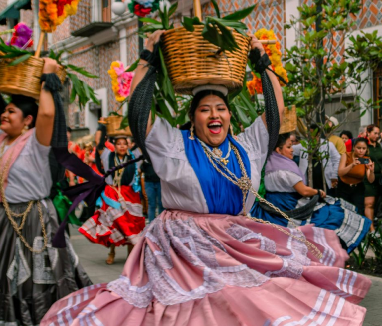 Dansende vrouw in Oaxaca met mand op hoofd en op de achtergrond meerdere dansende vrouwen