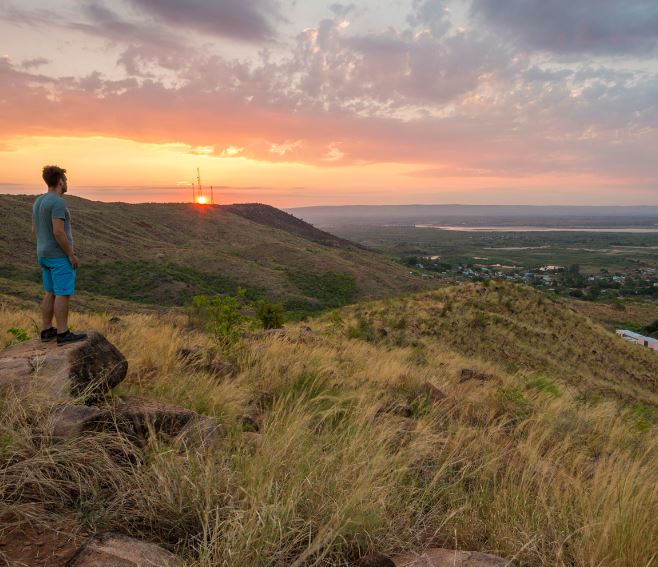 Reiziger kijkt naar het uitzicht vanuit de top van de heuvel met op de achtergrond de ondergaande zon in Madagaskar