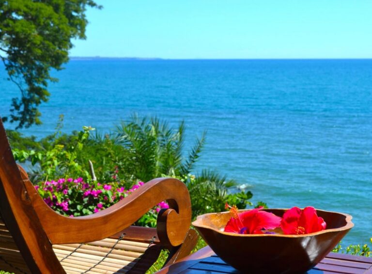 Ingezoomde stoel met tafel waarop een bak met bloemen staat, uitkijkend op de zee in Madagaskar