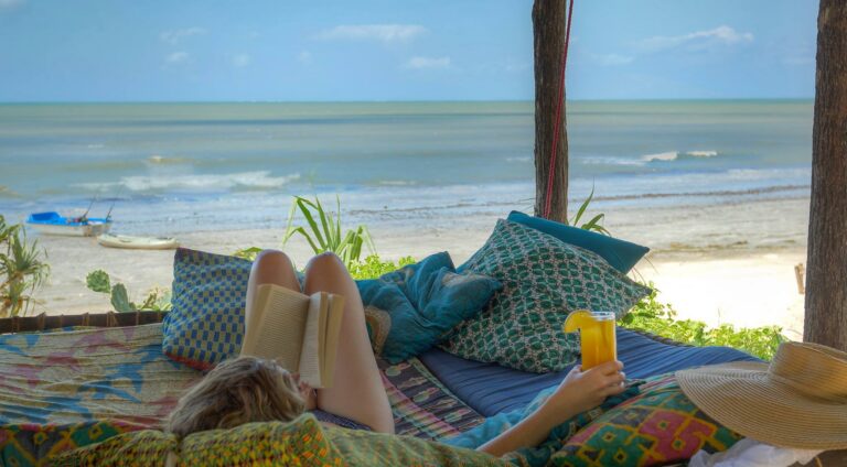 Reiziger bij het strand liggend op strandbed met boek en uitkijkend op de zee in Zanzibar