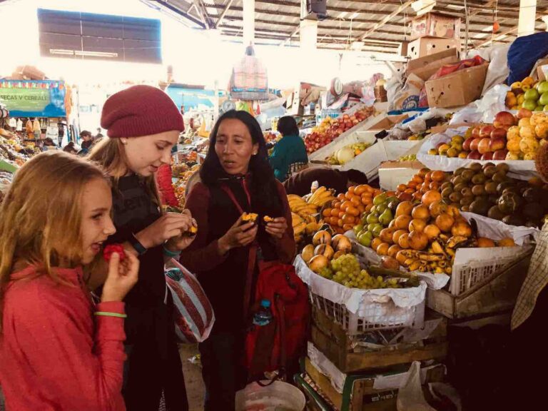 kinderen op de markt bij een fruitkraam met local die een stuk fruit proeven