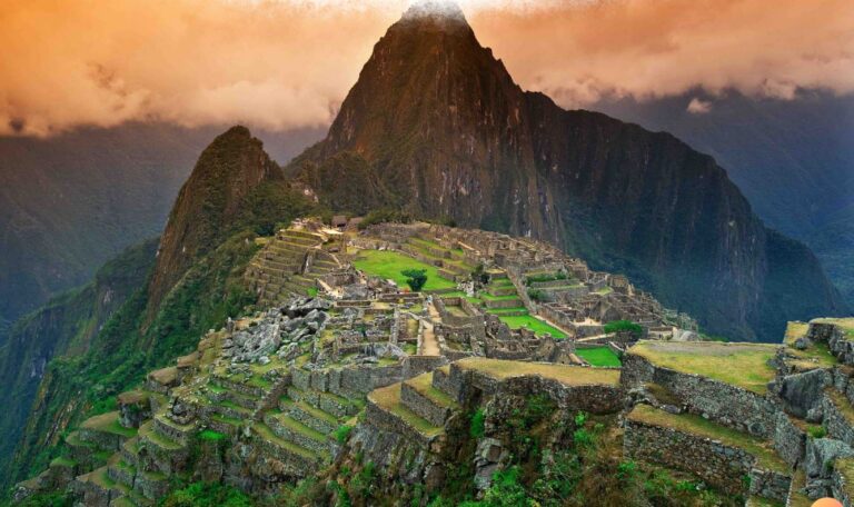 de ruïnes van machu picchu tussen de bergen met een oranje lucht