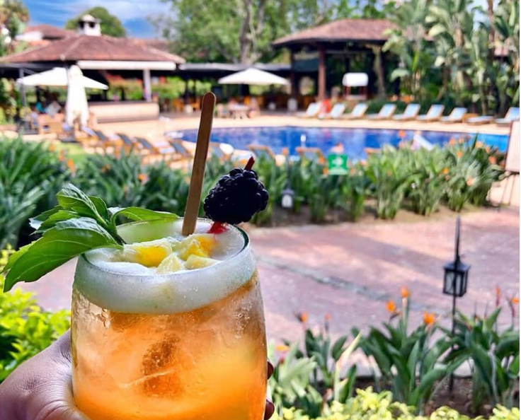 Cocktail met vaag op de achtergrond een zwembad met ligbedjes en een pad met planten