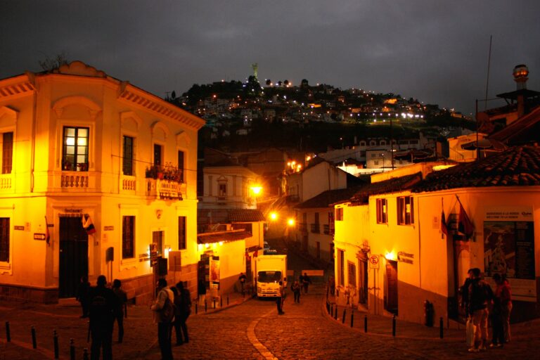 een straat in Quito bij nacht, op de achtergrond een berg met een verlicht beeld er op