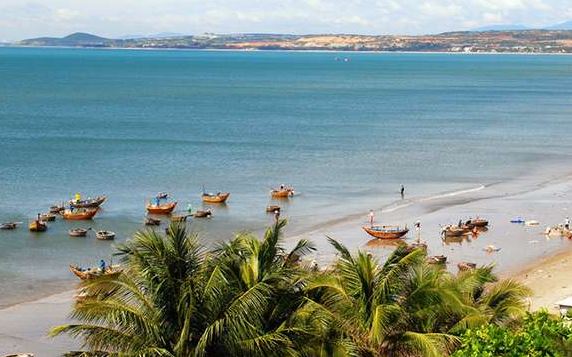 blauwe zee, wit strand en traditionele Vietnamese bootjes bij de kust