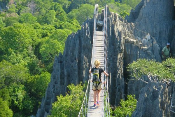 Vrouw op hangbrug omgeven door natuur in Madagaskar