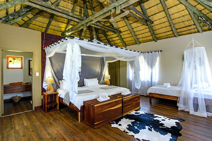 lodgekamer met wit hemelbed en rund vloerkleed op grond