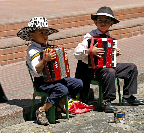 kinderen met hoedje op en accordeon zittend op stoeltjes in argentinië