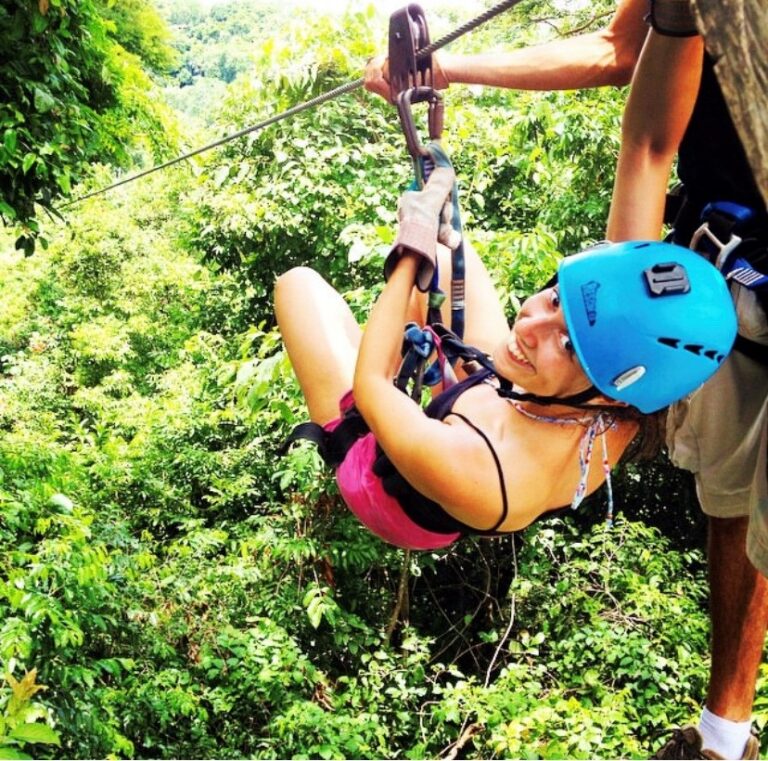 vrouw hangt aan zipline tussen groene boomtoppen monteverde