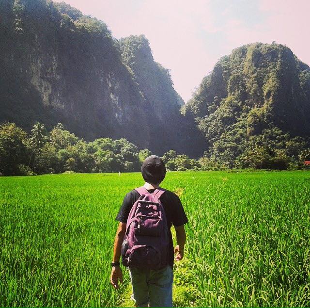 man wandelt via groene rijstvelden door het karstlandschap van Ramman Rammang in zuid-sulawesi
