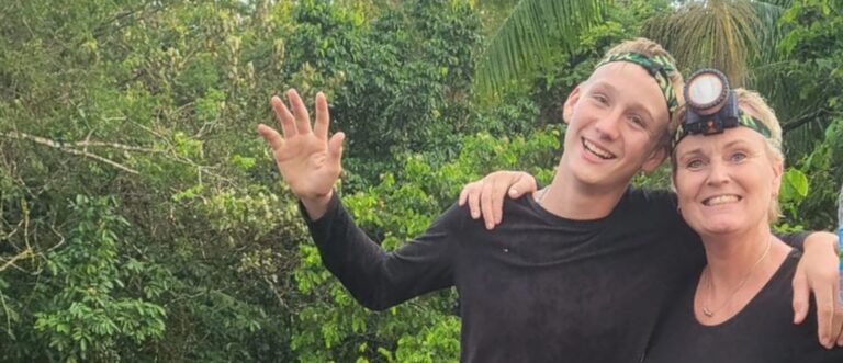 reizigers op houten dek zwaaien naar de camera midden in de jungle van Suriname