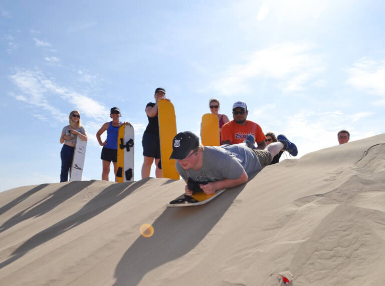 reizigers met boards die gaan sandboarden van de duinen