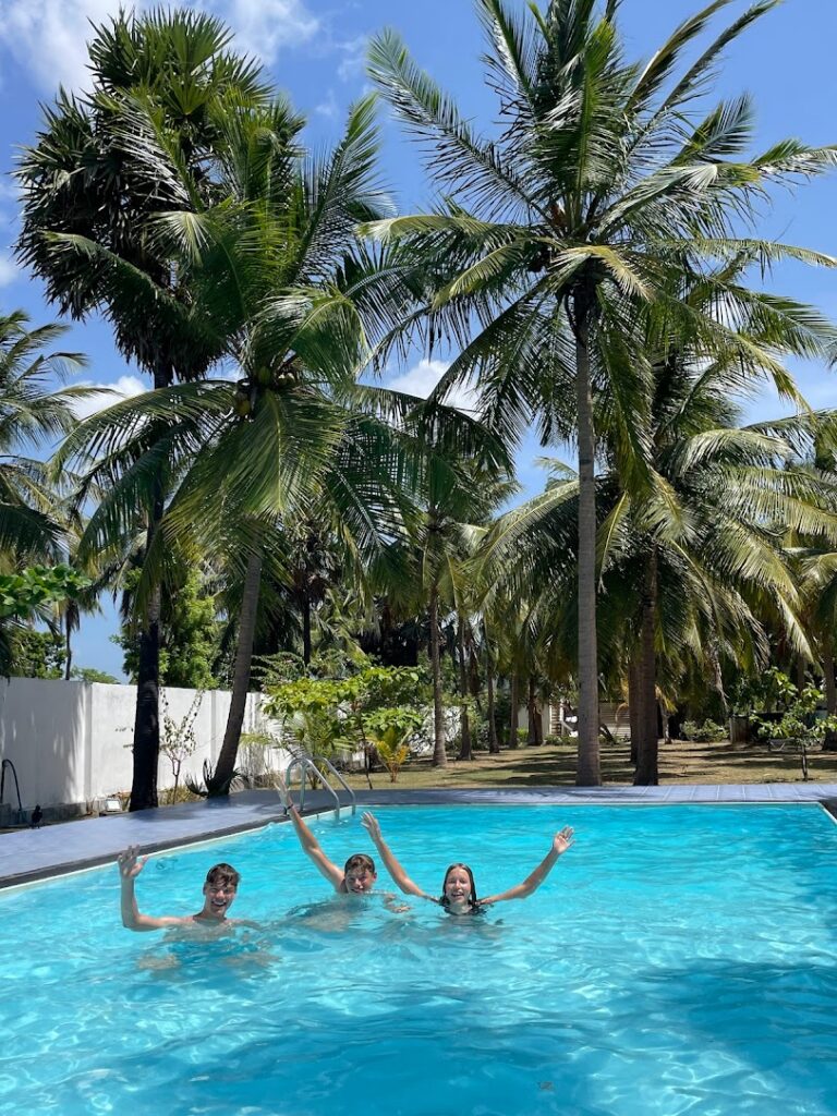 gezin springt in zwembad hotel Negombo omring door palmbomen