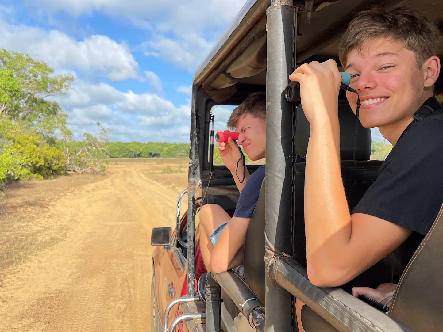 gezin op jeepsafari kijkend door verrekijkers in de Sri Lankaanse bush