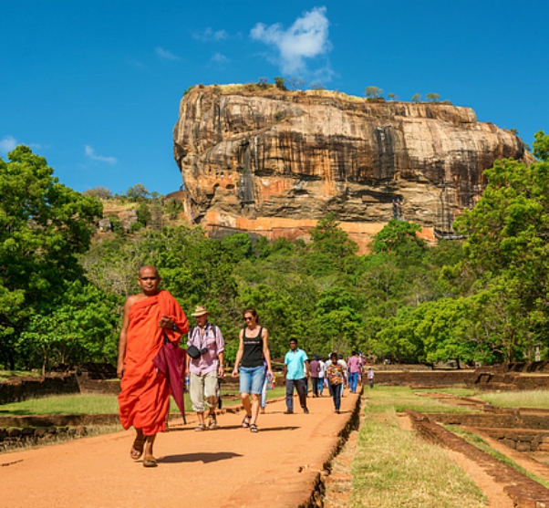 monnik in oranje gekleed loopt voor de beroemde leeuwenrots in sri lanka
