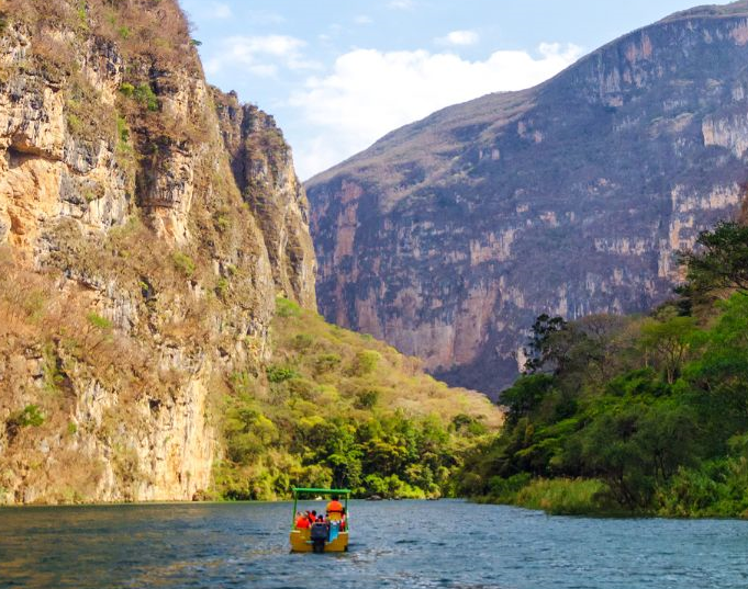 Bootje met reizigers op het water omringd door bergen en rotsen in Mexico