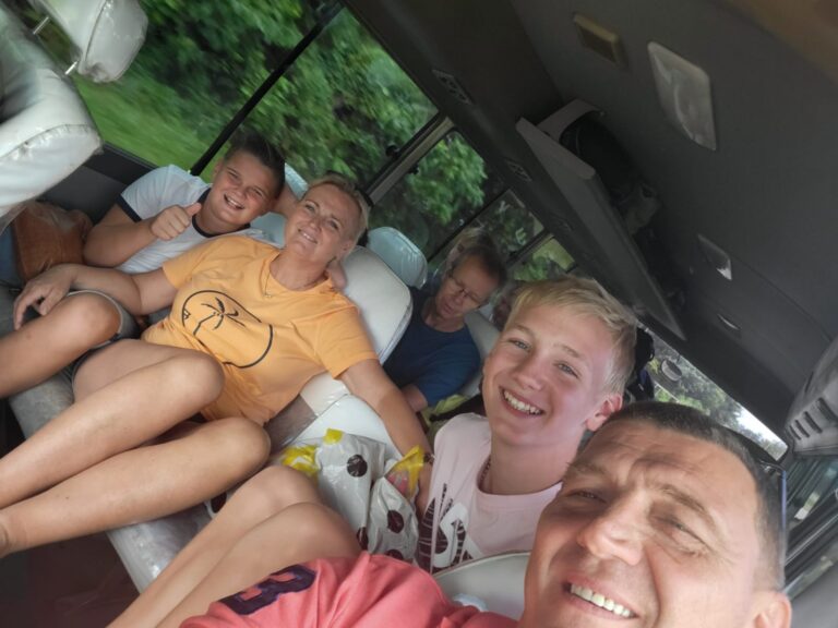 Lachend gezin in een open auto door het groen van suriname