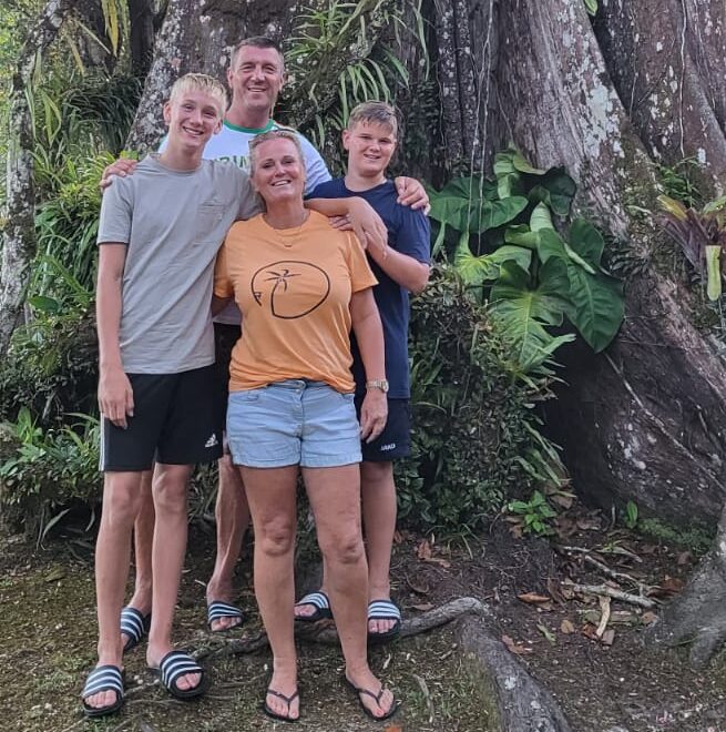 Een gezin van vier personen poseert voor een hoge boom in de jungle van Suriname
