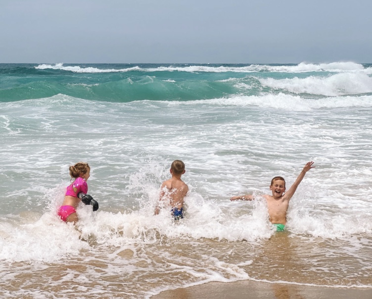 drie kinderen spelen in de branding van de zee