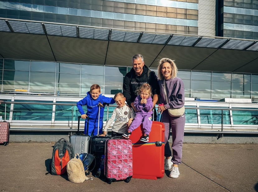 Gezin met kleine kinderen poserend op koffers voor Schiphol Airport