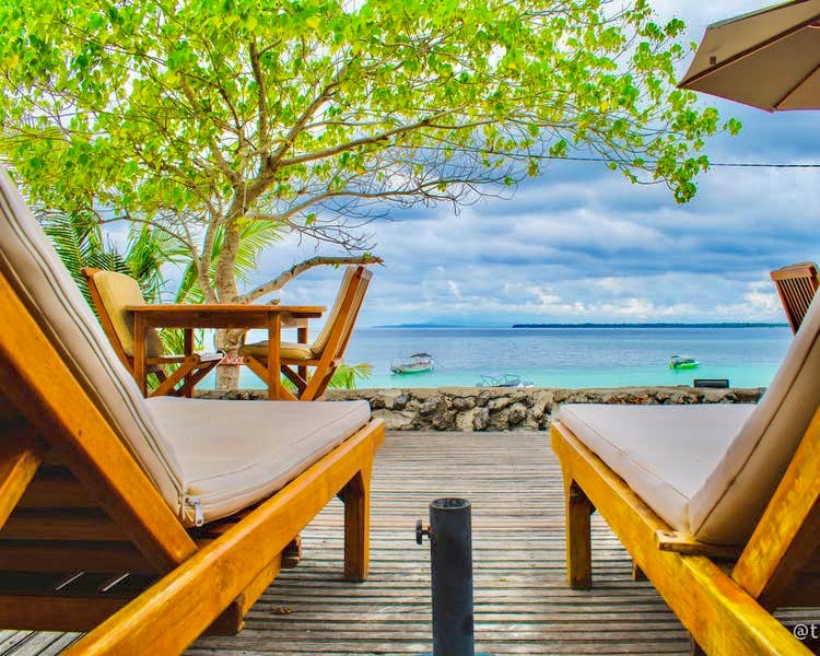 relax stoeltjes op vlonder aan zee tussen tropisch groen in bali