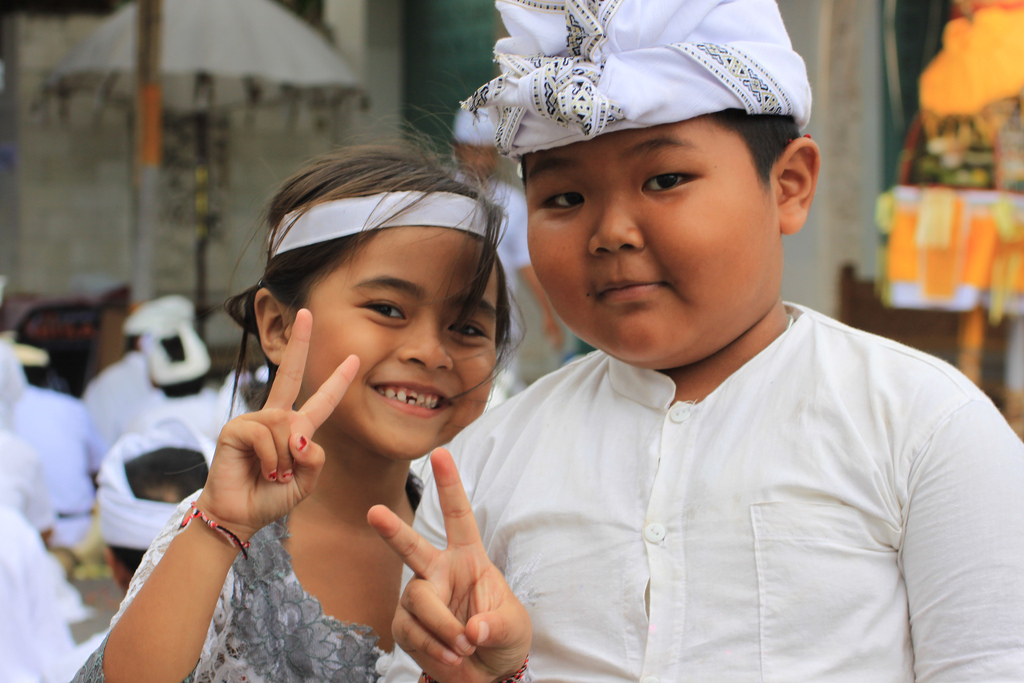 2 Balinese kinderen in traditionele kledij poserend met een peace teken