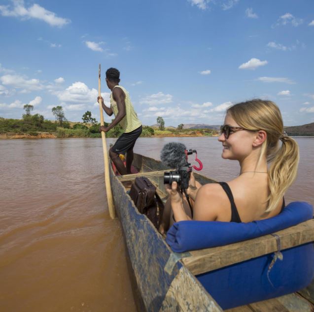 Reiziger met camera in hand in bootje en local bestuurt de boot op het water in Madagaskar