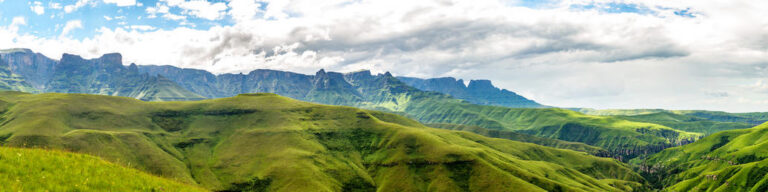 Landschapsfoto van Drakensberg met groene heuvels en een bewolkte lucht in Zuid-Afrika