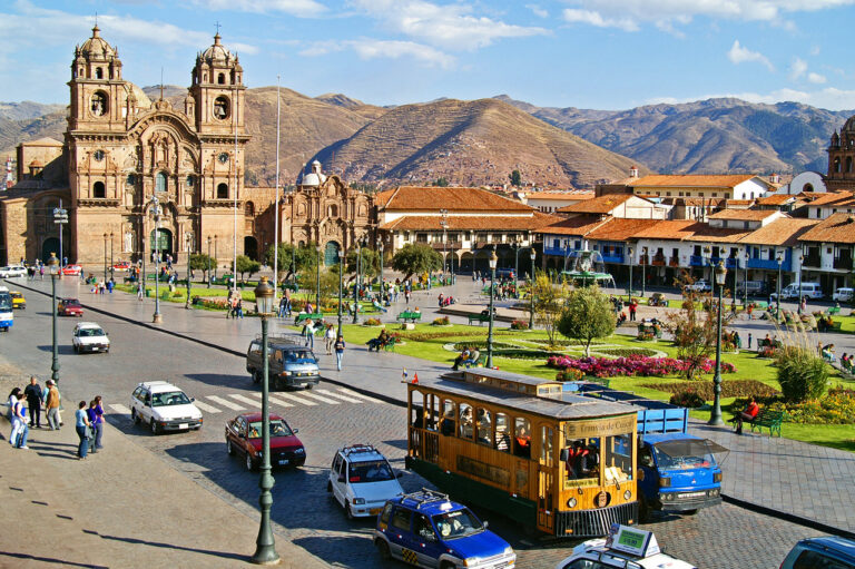 straat met kathedraal en gele tram en bergen op de achtergrond in cusco peru