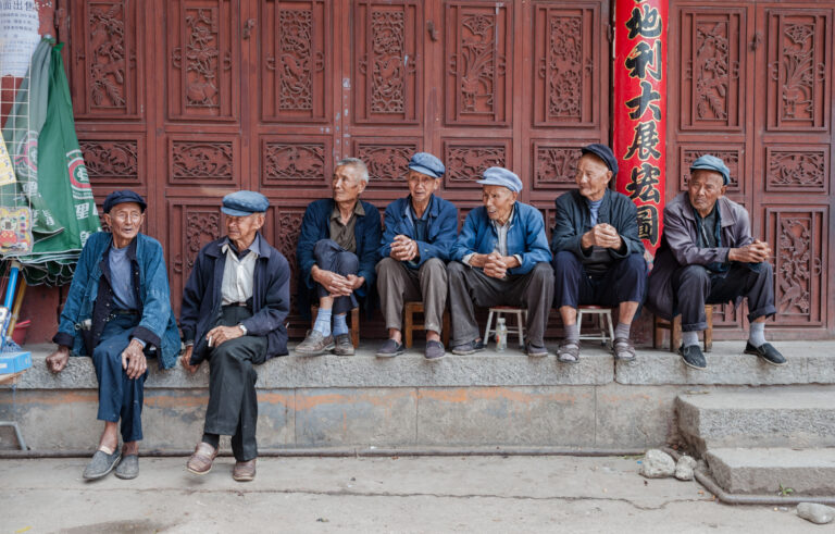 groep oudere Chinese mannen zit ontspannen voor een traditionele Chinese houten gevel